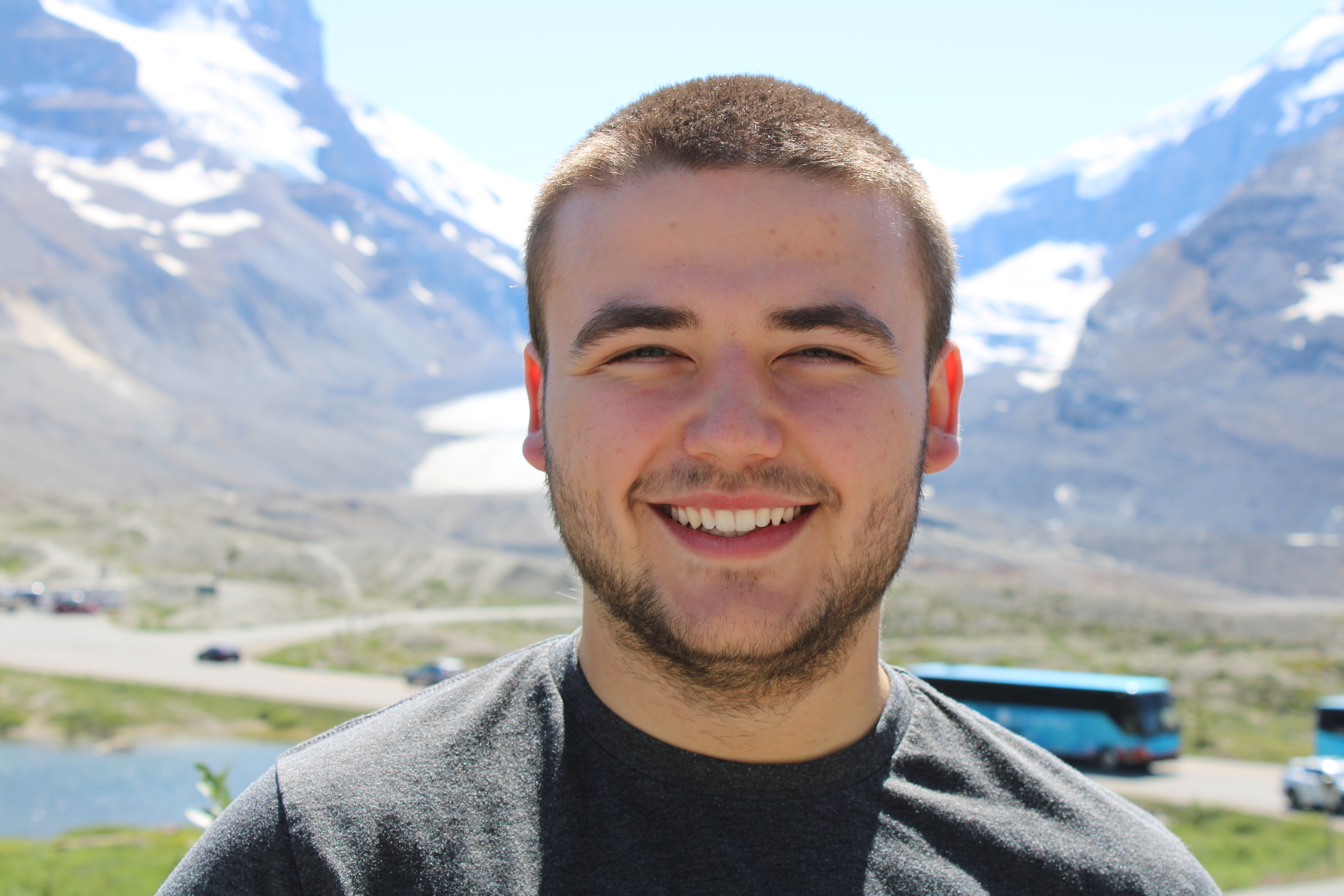 Close-up portrait of the Stratodora founder smiling, with a scenic mountain range and glacier in the background."